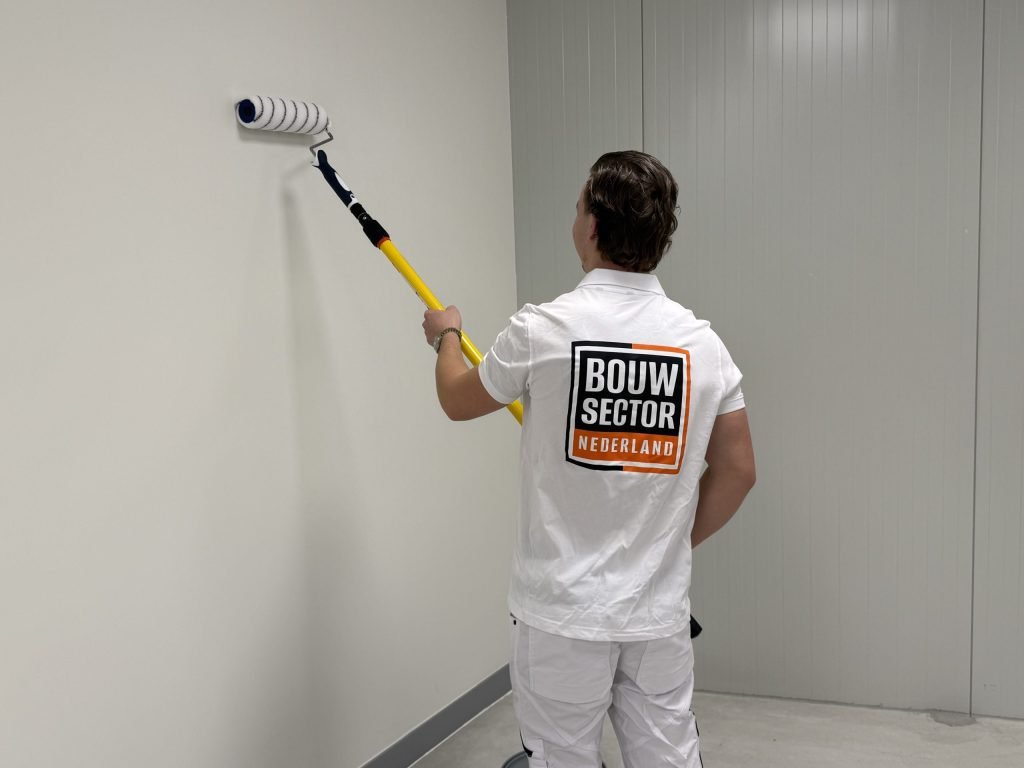 Schilder van Bouwsector Nederland zet de roller links bovenin op een lichte wand
